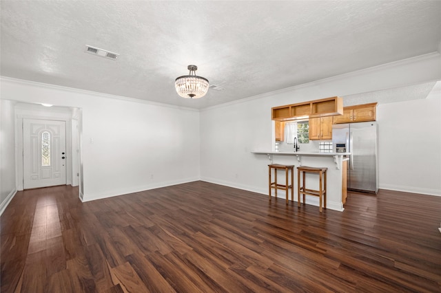 unfurnished living room featuring a notable chandelier, visible vents, a sink, and a healthy amount of sunlight