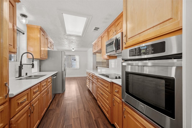 kitchen featuring dark wood finished floors, appliances with stainless steel finishes, light countertops, a sink, and baseboards