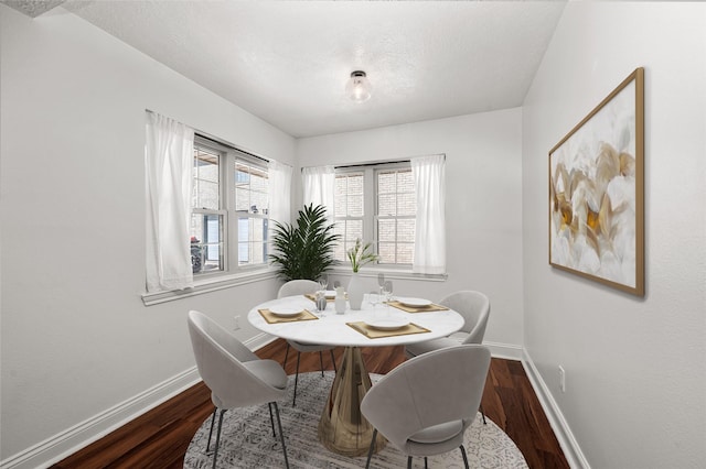 dining room with dark wood-type flooring, baseboards, and a textured ceiling