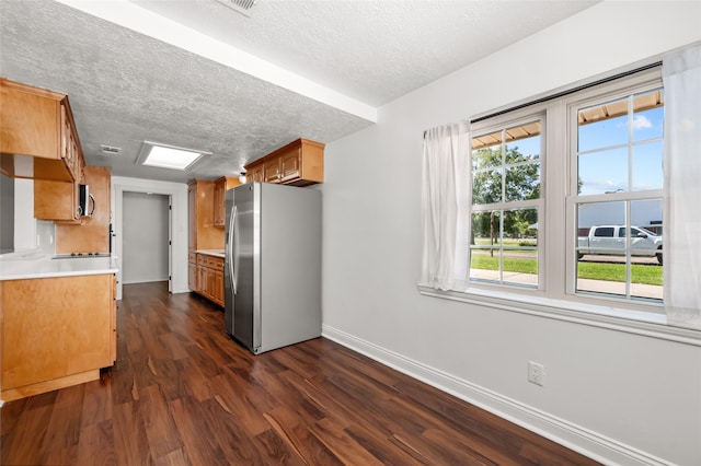 kitchen with stainless steel appliances, baseboards, a textured ceiling, and dark wood finished floors