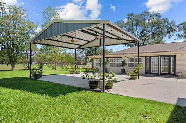 exterior space with a yard, a ceiling fan, brick siding, and a patio