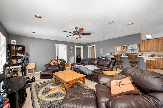 carpeted living room with ceiling fan and a textured ceiling