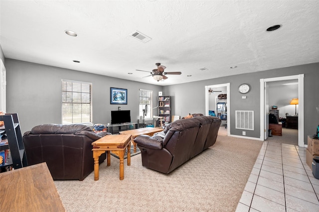 living area featuring light carpet, light tile patterned floors, visible vents, and ceiling fan