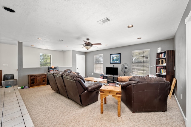 tiled living room with ceiling fan and a textured ceiling