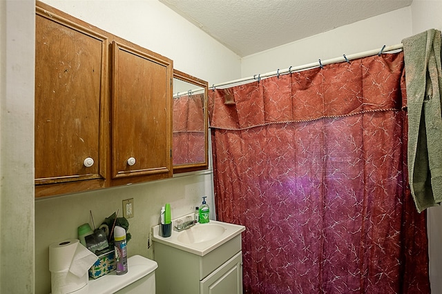 bathroom with vanity, walk in shower, toilet, and a textured ceiling