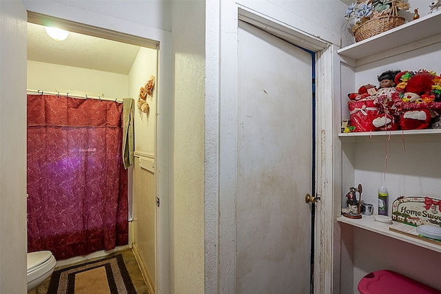 bathroom featuring a textured ceiling, toilet, and curtained shower