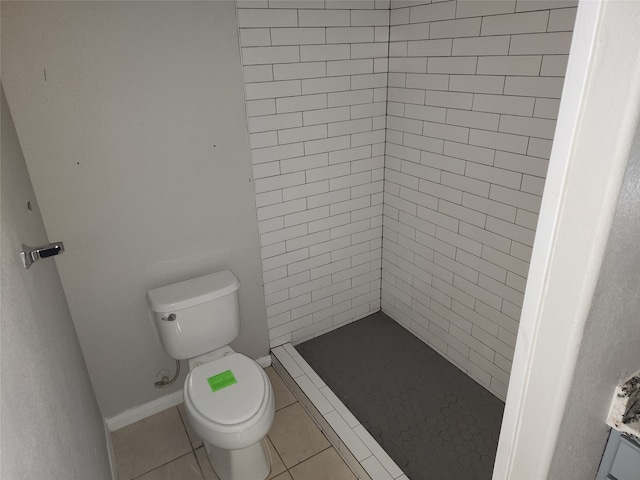 bathroom with tile patterned floors, a tile shower, and toilet