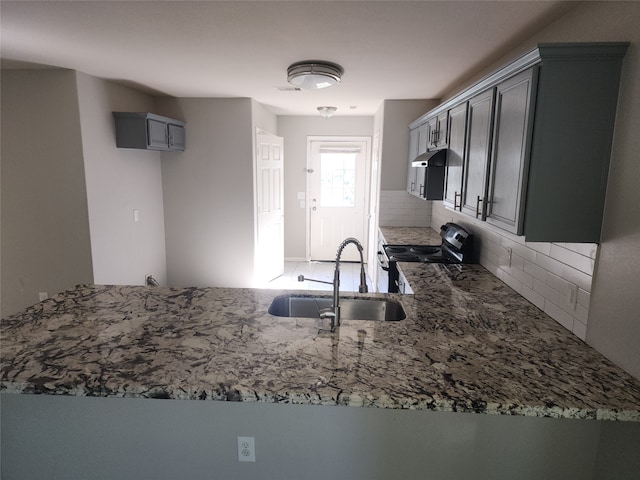 kitchen featuring sink, stainless steel appliances, kitchen peninsula, and stone countertops