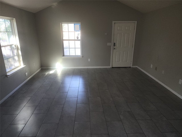 empty room featuring plenty of natural light and vaulted ceiling