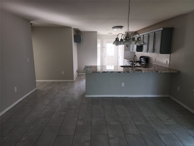 kitchen featuring pendant lighting, stone counters, a notable chandelier, decorative backsplash, and kitchen peninsula