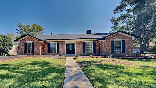 ranch-style home with a front lawn, a chimney, and brick siding