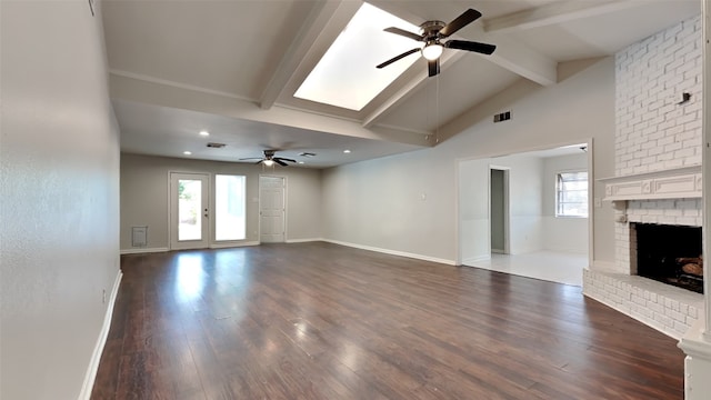 unfurnished living room with dark wood-type flooring, a brick fireplace, lofted ceiling with beams, and ceiling fan