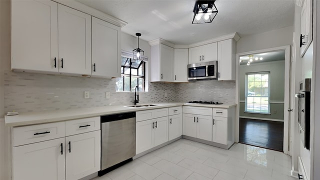 kitchen featuring sink, hanging light fixtures, white cabinetry, appliances with stainless steel finishes, and backsplash