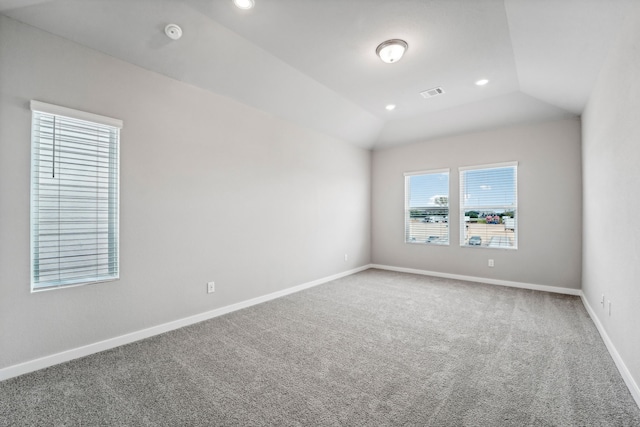 carpeted empty room featuring vaulted ceiling