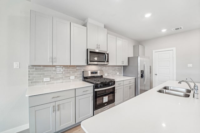 kitchen featuring backsplash, light hardwood / wood-style floors, sink, and appliances with stainless steel finishes