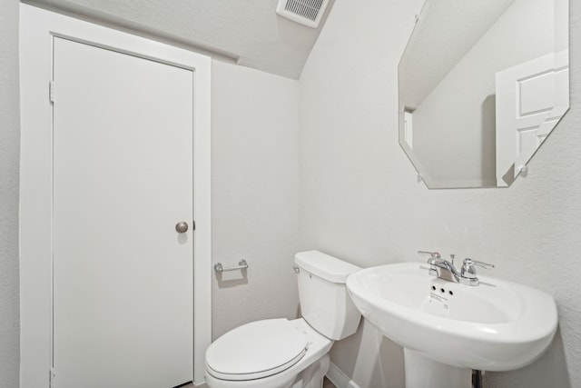 bathroom with vaulted ceiling, toilet, and sink