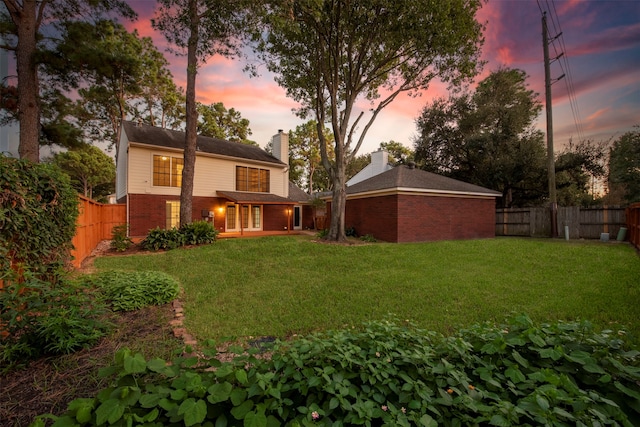 back house at dusk with a lawn