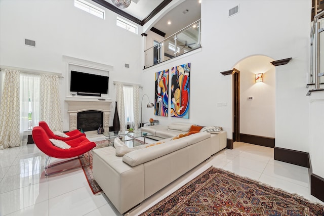 living room featuring ornate columns, a high ceiling, light tile patterned floors, and beamed ceiling