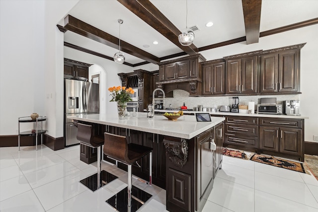 kitchen featuring beamed ceiling, decorative backsplash, a center island with sink, decorative light fixtures, and stainless steel appliances