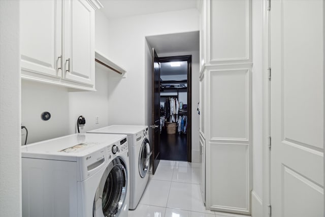 clothes washing area with washer and clothes dryer, cabinets, and light tile patterned floors