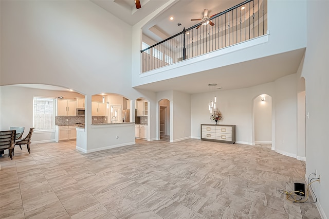 living room with ceiling fan, a towering ceiling, and sink