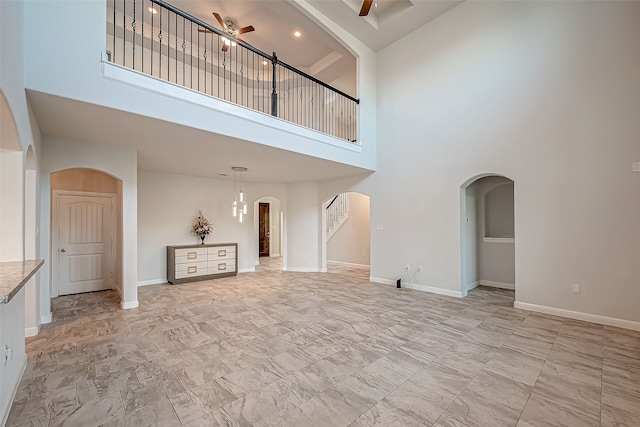 unfurnished living room featuring a high ceiling and ceiling fan