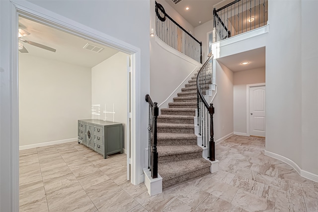 stairs featuring ceiling fan and a high ceiling