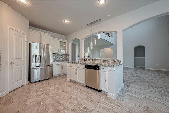 kitchen featuring white cabinets, stainless steel appliances, backsplash, and light stone countertops