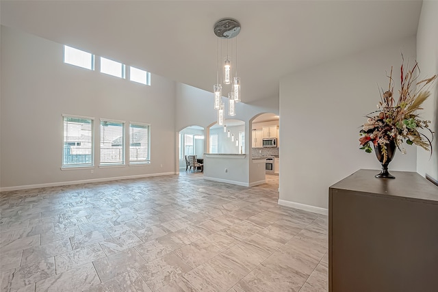 unfurnished living room featuring a notable chandelier and a towering ceiling