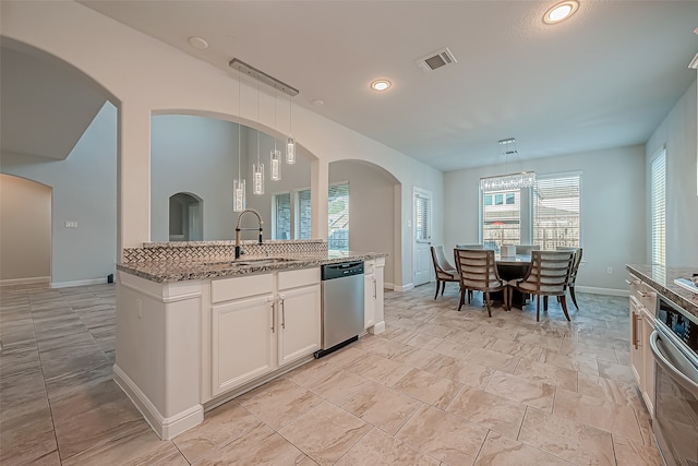 kitchen with light stone counters, pendant lighting, sink, white cabinetry, and appliances with stainless steel finishes