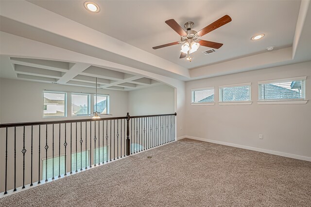 empty room with carpet floors, ceiling fan, coffered ceiling, and a healthy amount of sunlight