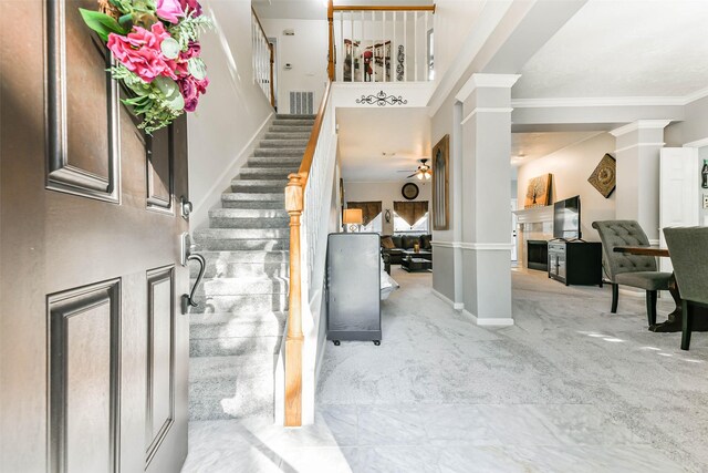 foyer entrance featuring light carpet, ceiling fan, ornamental molding, and decorative columns