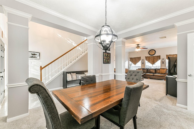 dining space featuring decorative columns, ceiling fan with notable chandelier, ornamental molding, and light carpet