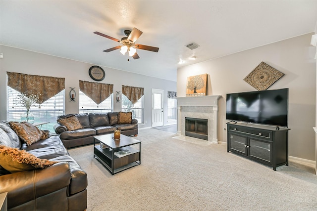 living room featuring ceiling fan, a high end fireplace, and light carpet