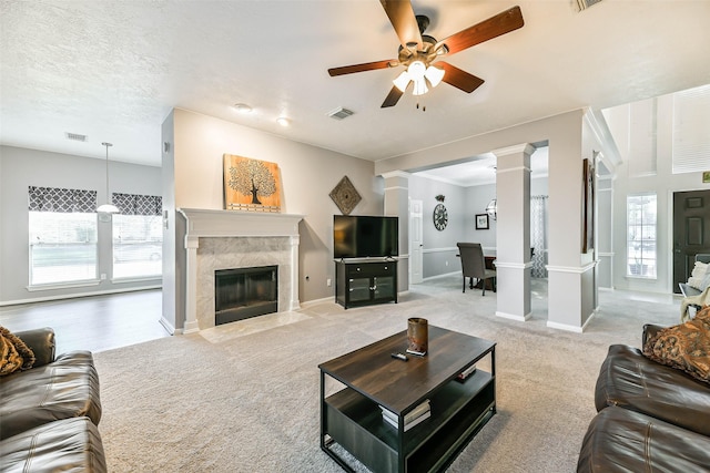 living room featuring light colored carpet, ornate columns, ceiling fan, and a high end fireplace