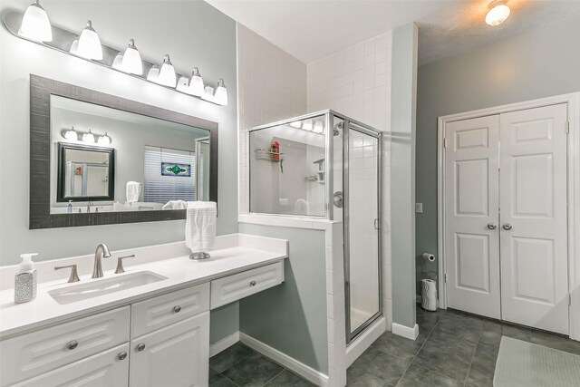 bathroom featuring a shower with shower door, tile patterned floors, and vanity