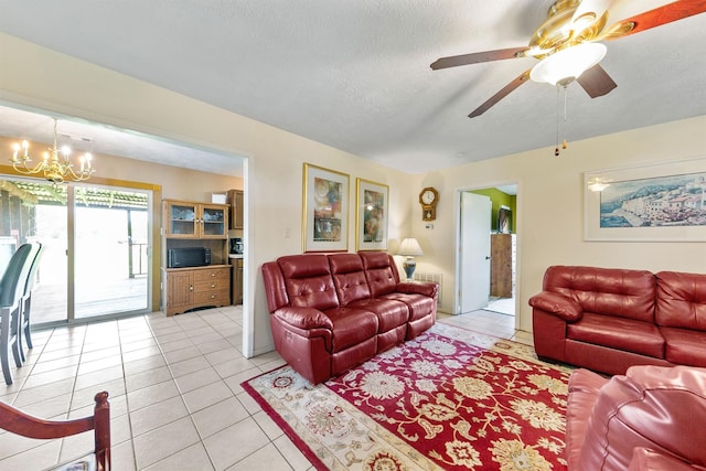 living room with ceiling fan with notable chandelier, light tile patterned flooring, and a textured ceiling