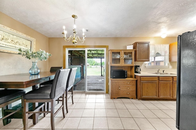 kitchen with pendant lighting, black appliances, plenty of natural light, and a textured ceiling