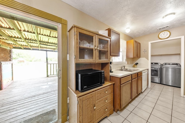 kitchen featuring a textured ceiling, white dishwasher, washing machine and clothes dryer, and light tile patterned flooring