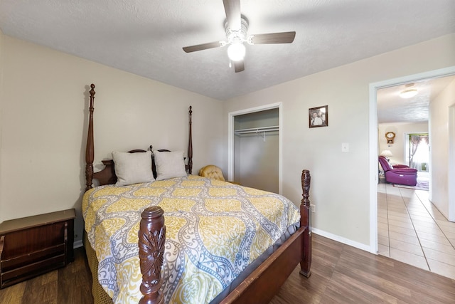 bedroom featuring ceiling fan, a textured ceiling, a closet, and dark wood-type flooring