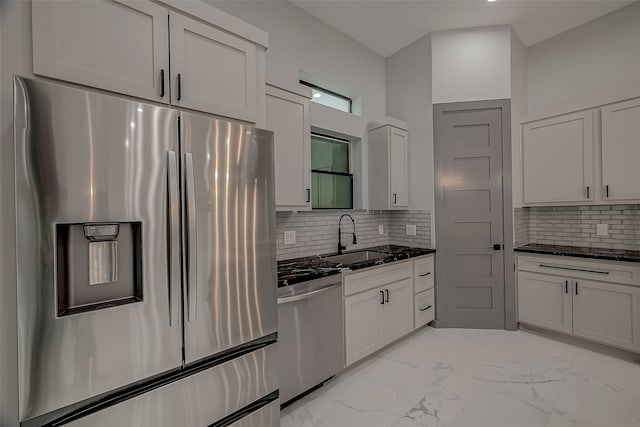 kitchen with stainless steel appliances, sink, tasteful backsplash, and white cabinetry