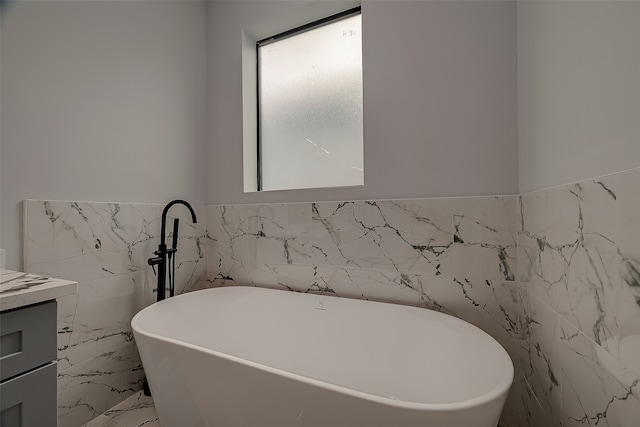 bathroom with a bathtub, vanity, and tile walls