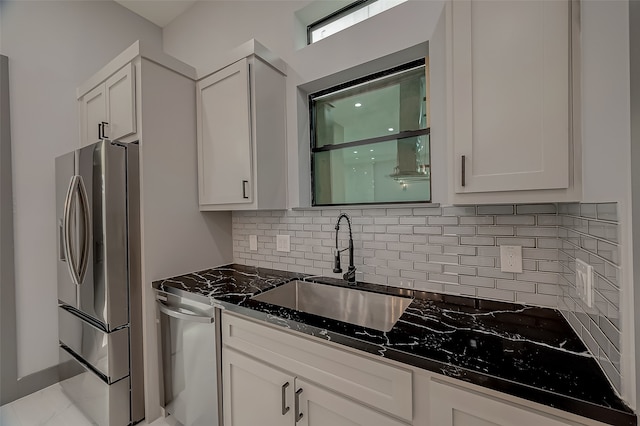 kitchen featuring stainless steel appliances, dark stone counters, sink, and white cabinetry