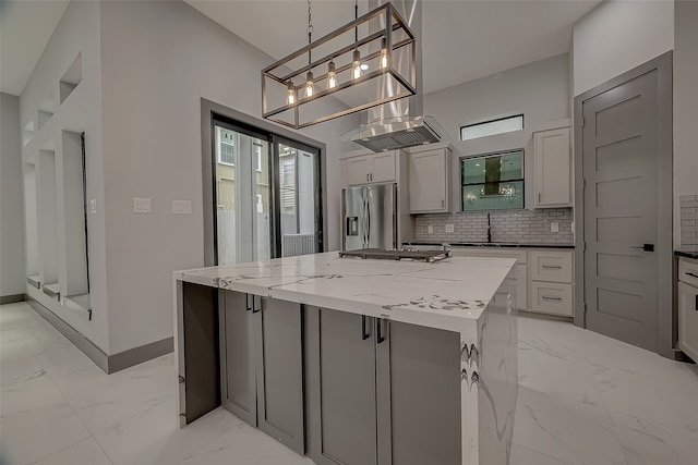 kitchen featuring light stone counters, stainless steel appliances, gray cabinetry, pendant lighting, and a center island with sink