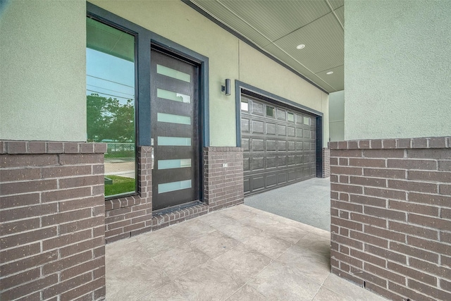 2322 Tuam, Houston, TX 77004 - view of exterior entry featuring stucco siding, driveway, brick siding, and an attached garage