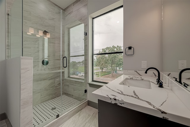 bathroom featuring a shower with door and vanity