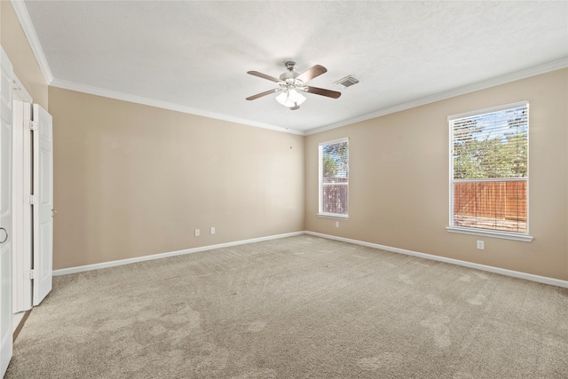 carpeted empty room featuring ceiling fan, plenty of natural light, and ornamental molding