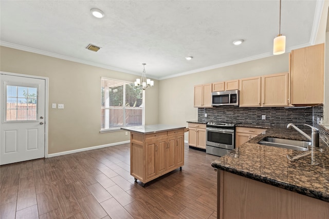 kitchen featuring decorative light fixtures, sink, appliances with stainless steel finishes, and a kitchen island