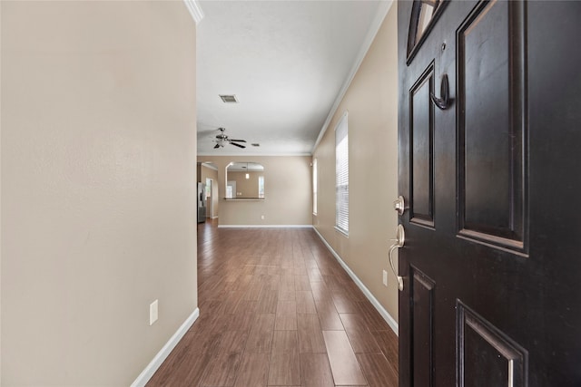 foyer entrance featuring dark wood-type flooring, ceiling fan, and ornamental molding