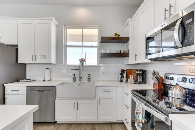 kitchen with white cabinets, stainless steel appliances, sink, and decorative backsplash